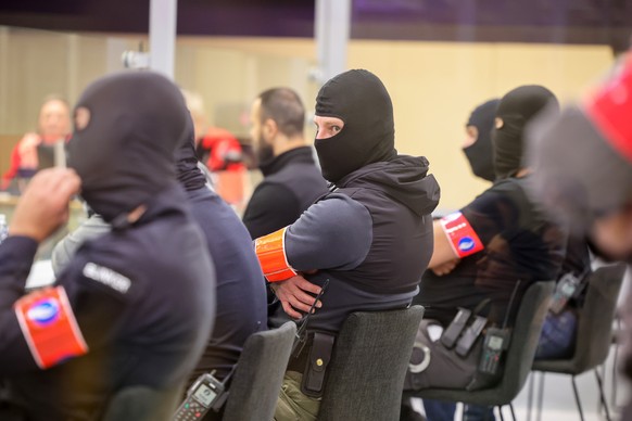epa10768195 Members of a Special Police Transfer team guard as defendants sit in a specially designed glass box in the courtroom at the start of the session of the 2016 Brussels terrorist attack trial ...