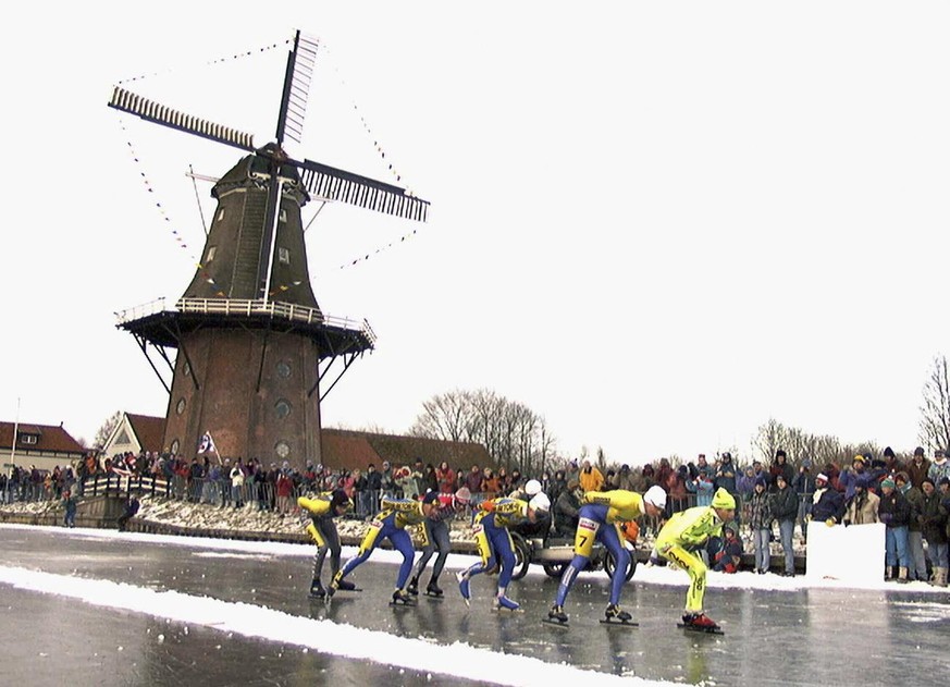 Schlittschuh-Läufer passieren eine Windmühle während der Elfstedentocht im Jahr 1997.