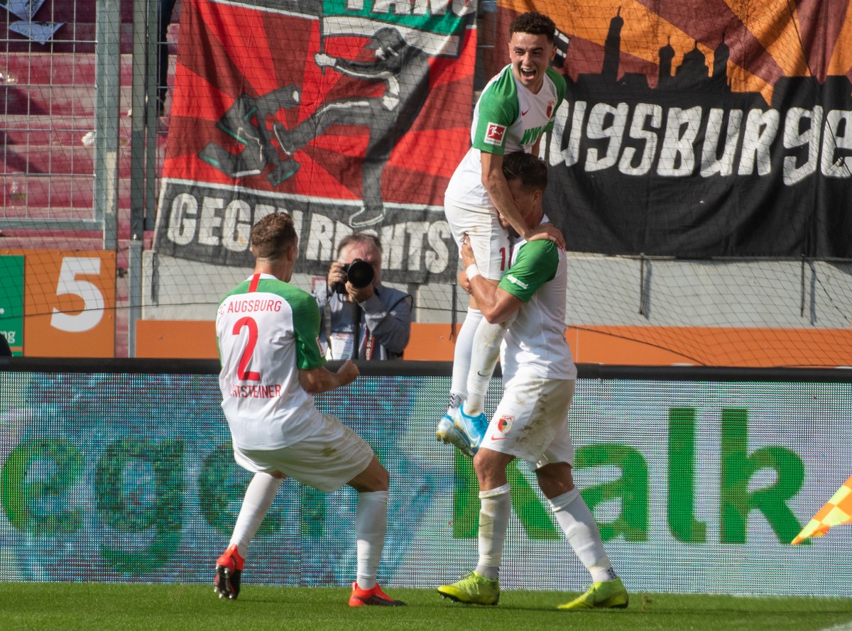 24.08.2019, Bayern, Augsburg: Fussball: Bundesliga, FC Augsburg - 1. FC Union Berlin, 2. Spieltag in der WWK-Arena. Augsburgs (l-r) Stephan Lichtsteiner, Ruben Vargas und Florian Niederlechner jubeln. ...