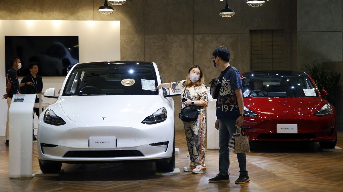 epa10677155 Potential customers inspect an all-electric Tesla Model Y (L) and Model 3 (R) cars displayed at a pop-up roadshow to promote its electric vehicles (EV) at a shopping mall in Bangkok, Thail ...