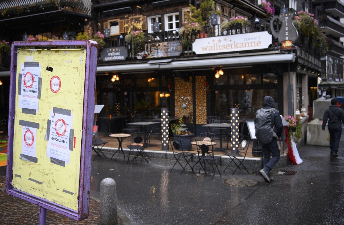 People walk past a sign that informs them that the restaurant is closed in front of the restaurant "Walliserkanne" after the restaurant was closed and the owners were arrested by the police  ...