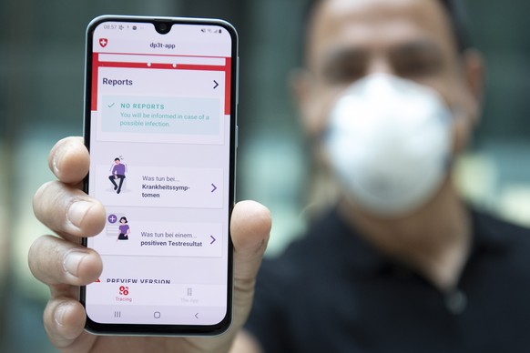 epa08381434 A person wearing protective face mask shows the smart phone app using Decentralized Privacy-Preserving Proximity Tracing (DP-3T) during a test with Swiss soldiers at the Swiss Federal Inst ...