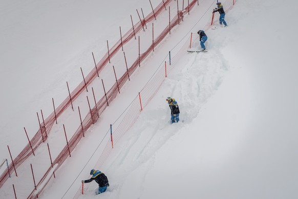 epa08863392 Volunteers work on the ski slope, in St. Moritz, Switzerland, 05 December 2020. Due to a heavy snowfall and strong wind, the FIS decided to cancel the women&#039;s Super-G race of the FIS  ...