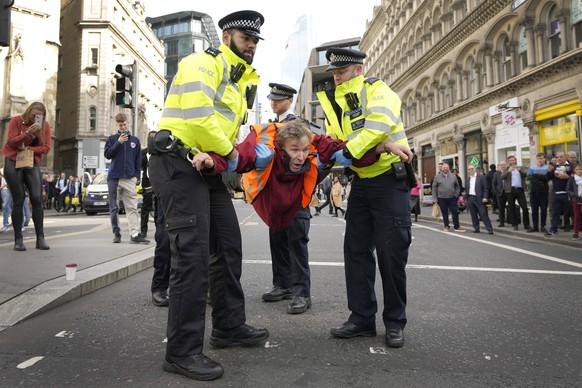 Police officers arrest an activisit from the group Just Stop Oil after they blocked a road in London, Thursday, Oct. 27, 2022 demanding to stop future gas and oil projects from going ahead. (AP Photo/ ...