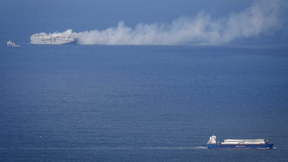 epa10770009 A cargo ship passes the Fremantle Highway that is on fire in the North Sea north of Ameland, the Netherlands, 26 July 2023. A fire broke out overnight on 26 July on the Fremantle Highway,  ...