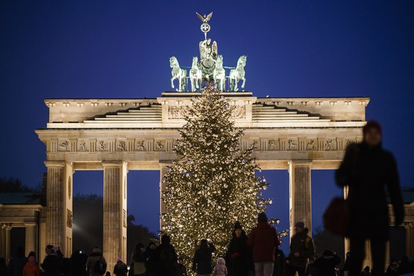 epa10344569 Passers-by walk in front of a Christmas tree at the Brandenburg Gate in Berlin, Germany, 02 December 2022. Christmas markets and Christmas trees on public spaces are part of the traditiona ...