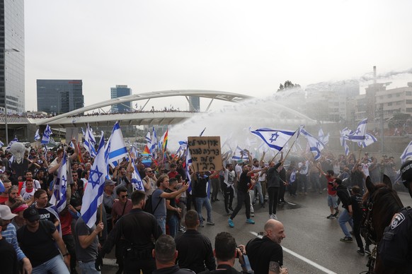epa10538508 Protesters blocking the Ayalon Highway react as police (not pictured) use water cannons during a rally against the Israeli government&#039;s planned reform of the justice system, in Tel Av ...