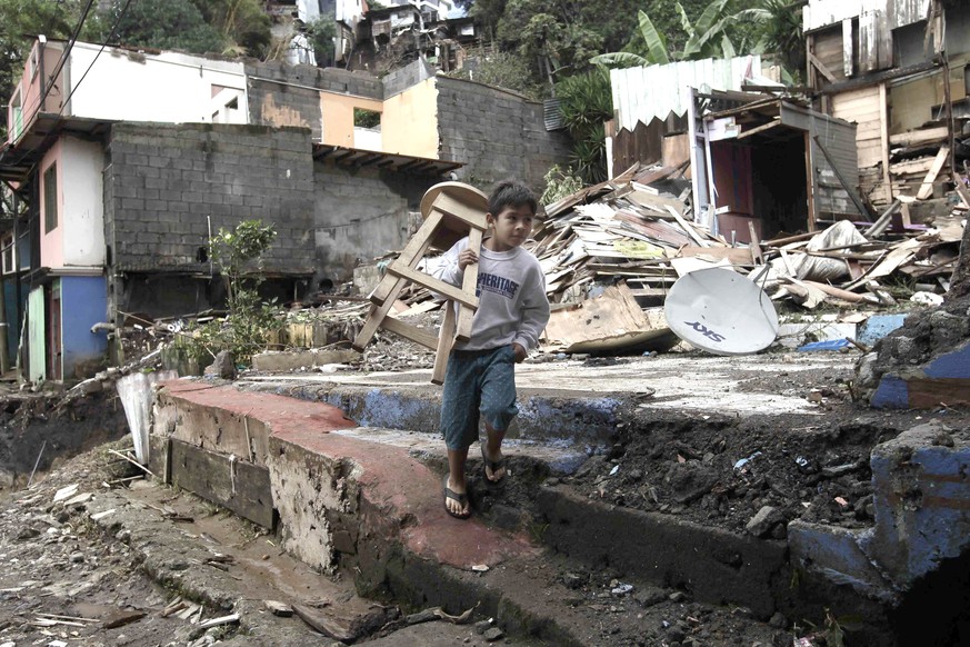 epa06249193 A boy carries a chair in the middle of the rubble of several houses after the passage of the tropical storm Nate, at the neighborhood of Los Anonos, in the canton of Escazu, west of San Jo ...