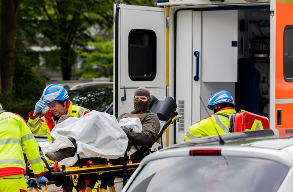11.05.2023, Nordrhein-Westfalen, Ratingen: Ein verletzter Polizeibeamter wird vor einem Hochhaus in einen Krankenwagen gebracht. Bei einer Explosion in einem Hochhaus in Ratingen am Donnerstagvormitta ...