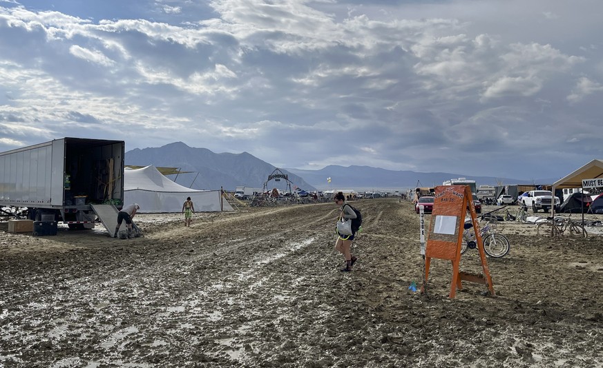 epa10838247 A person walks in the mud at the Burning Man Festival in the Black Rock Desert, Nevada, USA, 03 September 2023. Heavy rains in the normal dry location created deep, heavy mud conditions th ...