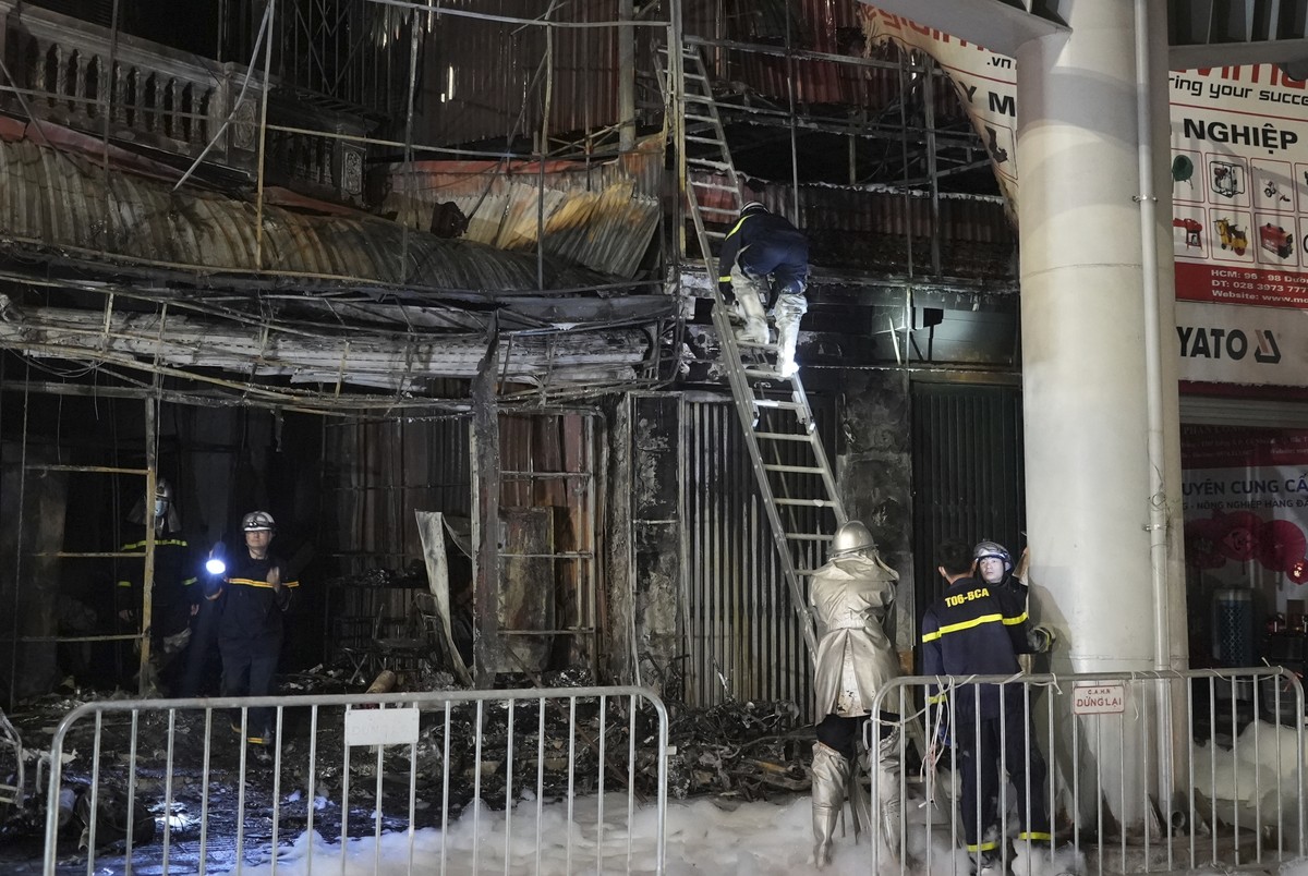 Fire personnel inspect a building burned down by a fire in Hanoi, Vietnam on Thursday, Dec.19, 2024. (AP Photo/Hau Dinh)