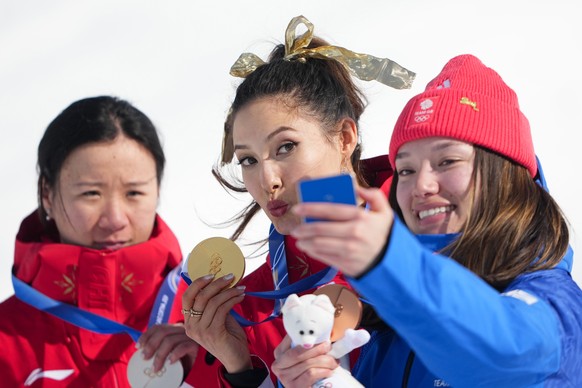 From left, silver medalist China's Li Fanghui, gold medalist China's Eileen Gu and bronze medalist Britain's Zoe Atkin take a selfie after the women's freestyle skiing halfpipe fin ...