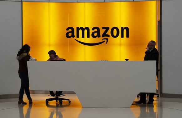 FILE - In this Feb. 14, 2019 file photo, people stand in the lobby for Amazon offices in New York. While other companies are shrinking, Amazon is growing. The company said Wednesday, Sept. 9, 2020, th ...