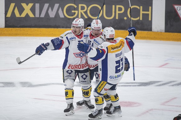 From left, Kloten's player Arttu Routsalainen, Kloten's player Miro Aaltonen and Jordann Bougro, celebrate the 4-5 goal, during the preliminary round game of the National League 2022/23 between HC Lug ...