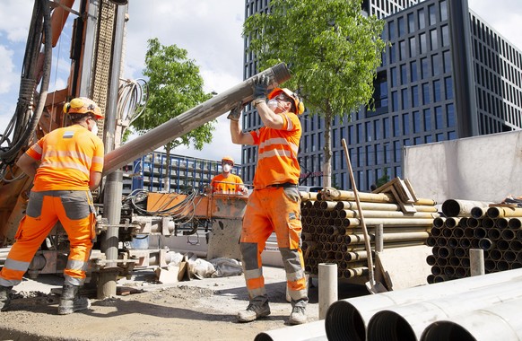 epa08387353 Workers wearing protective face masks, as recommended by Swiss authorities as a precaution against the spread of the coronavirus COVID-19, remove drilling tubes at a construction site in G ...