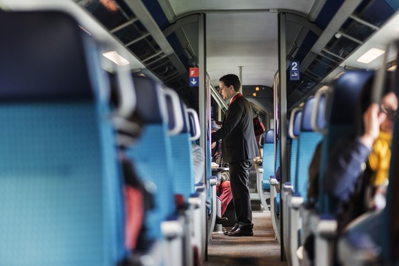 ARCHIVBILD ZUR GEPLANTEN RUECKKEHR ZUM NORMALEN FAHRPLAN --- A train conductor of the Swiss Federal Railways checks passenger&#039;s tickets on a train travelling from Zurich to Lucerne, Switzerland,  ...