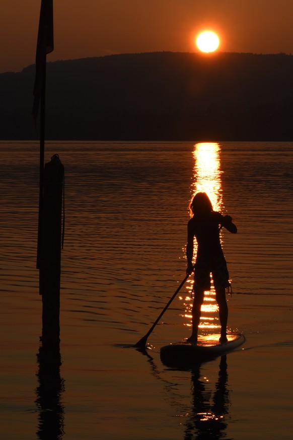 A woman paddles with her surfboard at sunset near Reichenau Island on Lake Constance, southern Germany on October 3, 2014. AFP PHOTO / DPA / FELIX KÄSTLE +++ GERMANY OUT