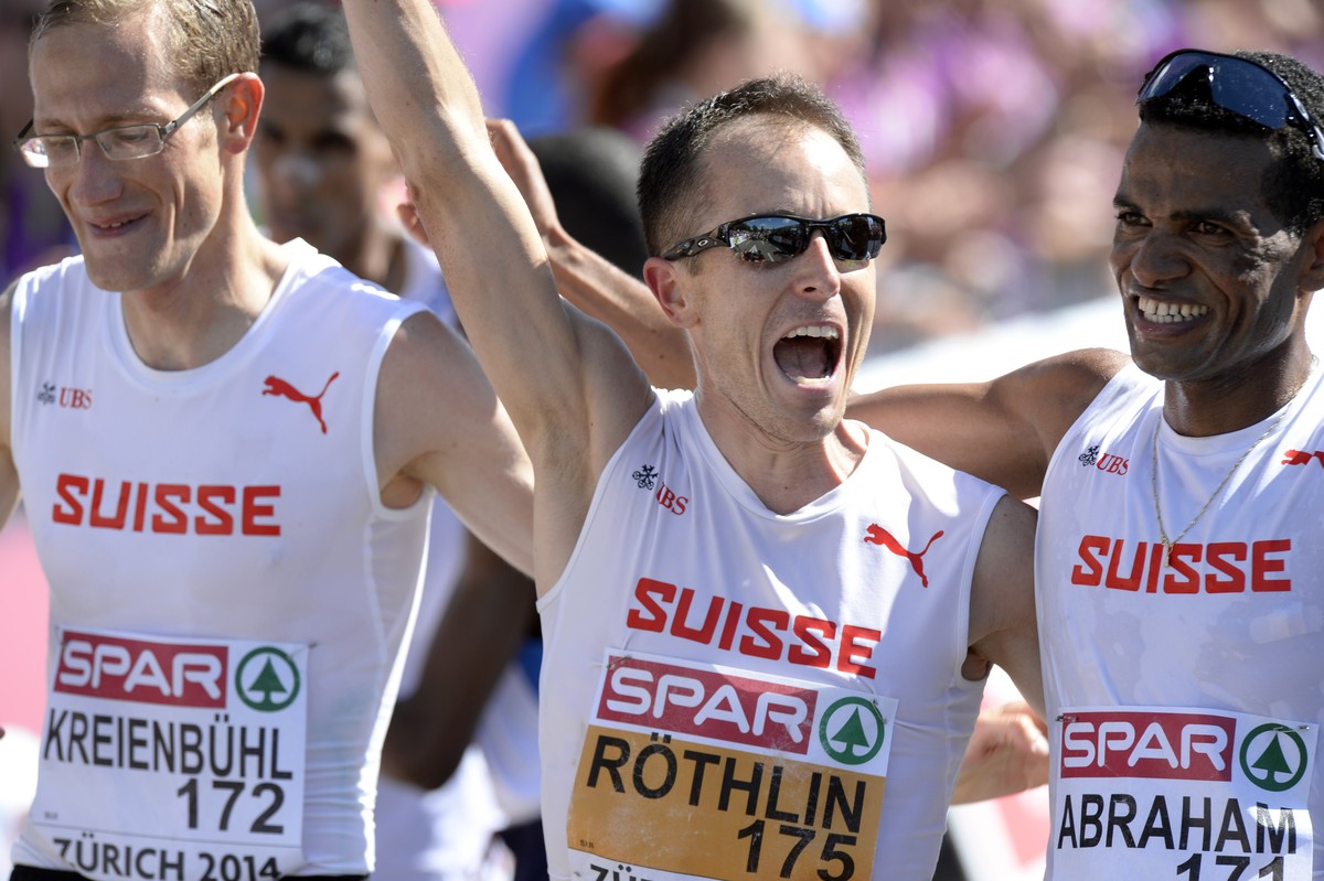 Switzerland's Viktor Roethlin, centre, Tadesse Abraham, right, and Christian Kreienbuehl, left, cheer after winning the team event bronze medal in the men's Marathon in the city centre of Zu ...