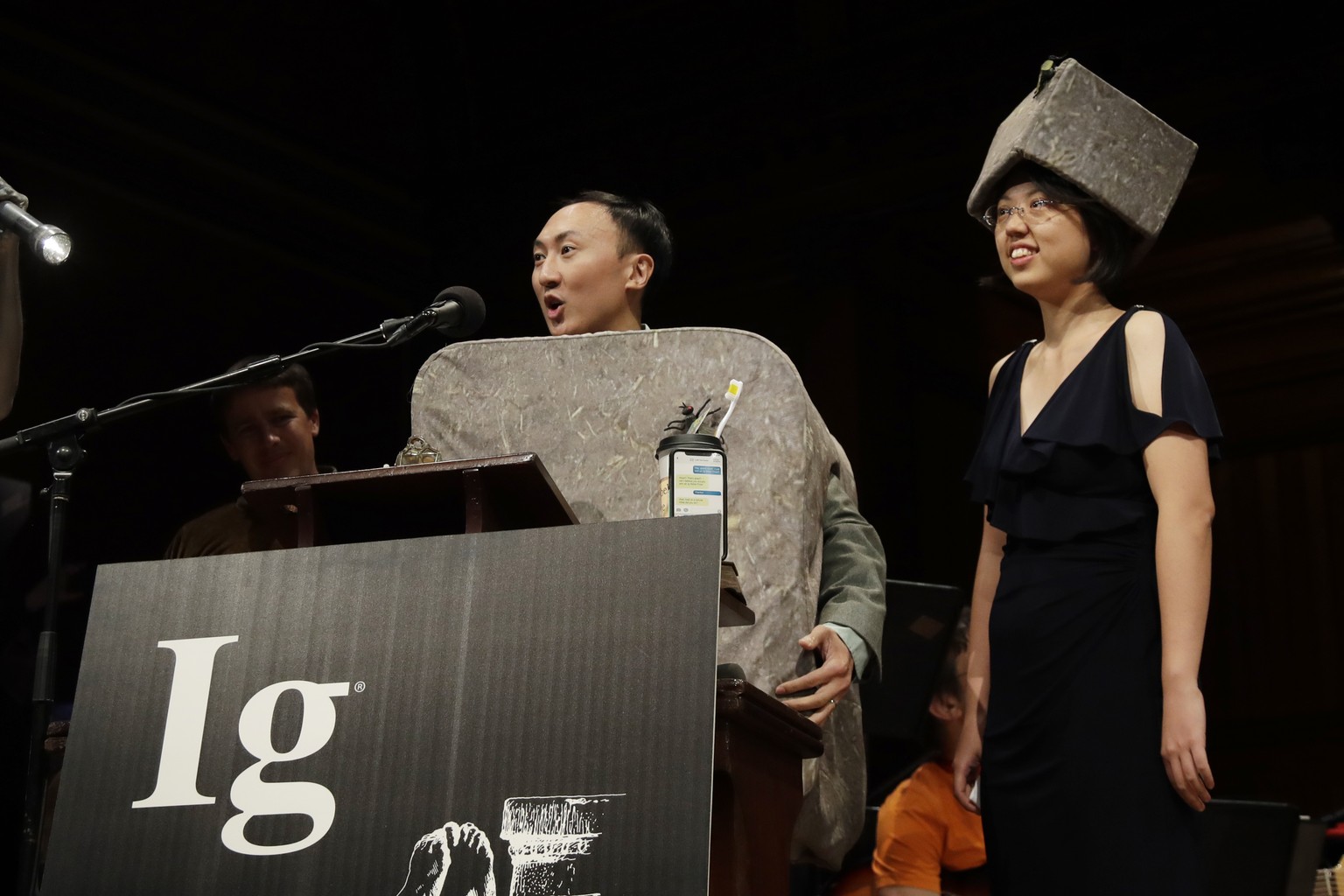 David Hu speaks as Patricia Yang, right, listens as they receive the Ig Nobel award in physics for studying how and why wombats make cubed poo, at the 29th annual Ig Nobel awards ceremony at Harvard U ...