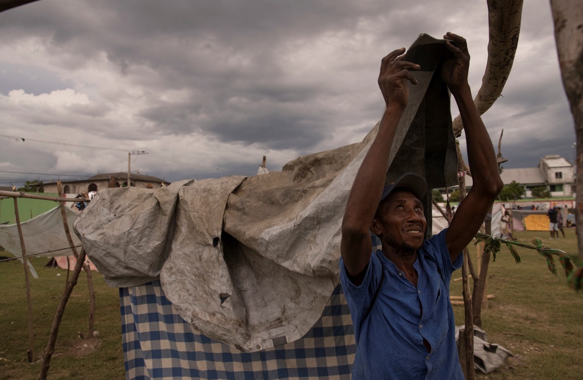 epa09417286 A person sets up tents in a makeshift camp, as the rains from Tropical Depression Grace arrive, in Les Cayes, Haiti, 16 August 2021. The authorities in Haiti increased the number of deaths ...