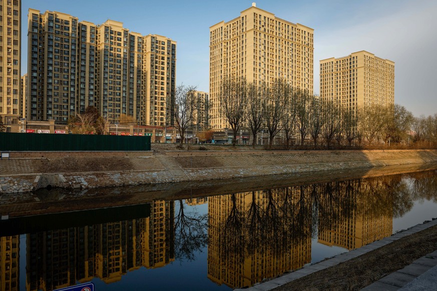 epa11010395 An Evergrande housing complex is reflected on a river in Beijing, China, 04 December 2023. China Evergrande Group&#039;s court hearing into a liquidation petition was postponed by a Hong K ...