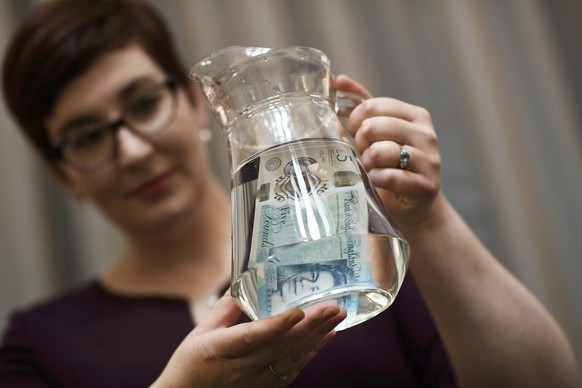 Bank of England Museum curator Jenni Adam, shows off the waterproof properties of the new polymer five pound note during an event at the Bank of England in central London, Britain September 6, 2016. T ...