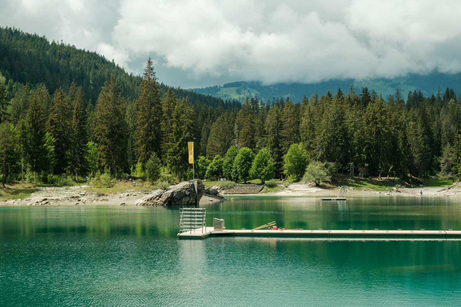 A beautiful view of the Caumasee lake under a cloudy sky near Flims, in the Grisons, Switzerland xkwx alps beach caumasee cloudy coast daytime environment flims forest green grisons hills lake landsca ...