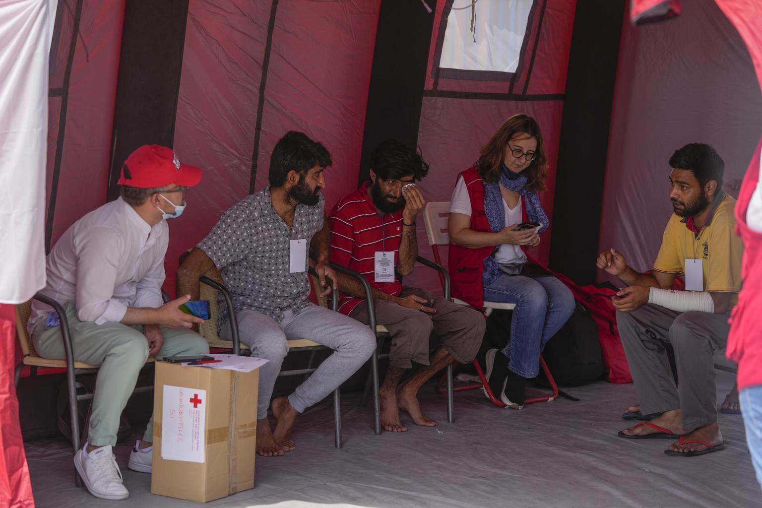 Survivors of a shipwreck speak with Red Cross volunteers outside a warehouse at the port in Kalamata town, about 240 kilometers (150miles) southwest of Athens, Thursday, June 15, 2023. A fishing boat ...