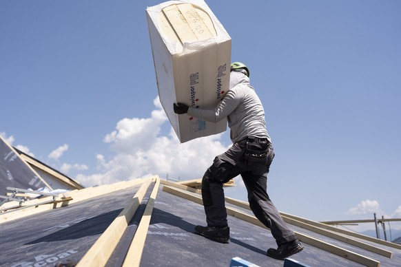 Ein Mitarbeiter der Greencover AG arbeitet an der Sanierung und Neuisolierung eines Daches bei grosser Hitze und starker Sonne, fotografiert am Mittwoch, 24. Juni 2026 in Mels (KEYSTONE/Gaetan Bally)