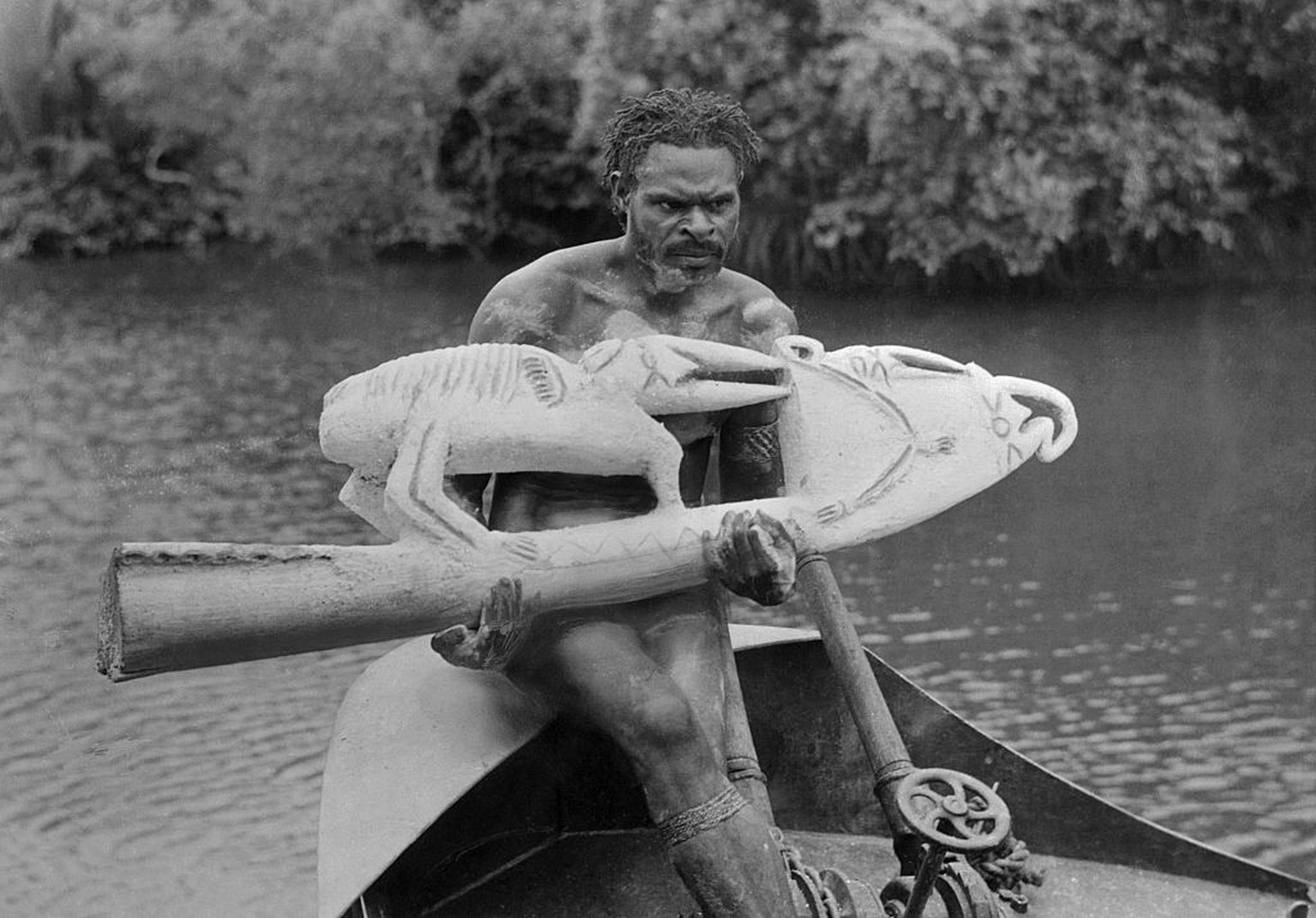 (Original Caption) A native of New Guinea holds a piece of primitive art here, made in a bird-like appearance and used as the stern of a native boat. This photo gives some idea of the type of primitiv ...
