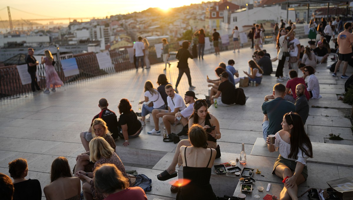 People watch the sun set from a viewpoint overlooking the Tagus river in Lisbon, Friday, Oct. 8, 2021. Portugal has scrapped many of its remaining COVID-19 restrictions, after becoming the world leade ...