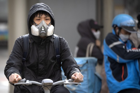 A person in a gas mask rides a bicycle during a dust and sand storm in the central business district in Beijing, Tuesday, April 11, 2023. The latest in a series of dust and sand storms sent air...