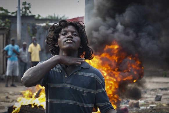 epa04770796 A Burundian protester gestures in front of a burning barricade as he and others face police officers and soldiers during an anti-government demonstration against President Pierre Nkurunziz ...