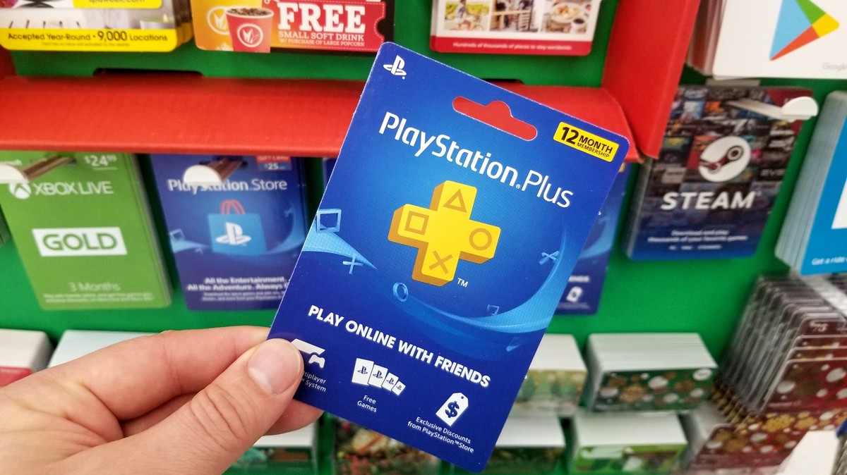 PLATTSBURGH, USA - JANUARY 21, 2019 : Play Station Plus 12 month membership gift card in a hand over a shelves with different giftcards in a Walmart store. xkwx playstation, play, station, plus, membe ...