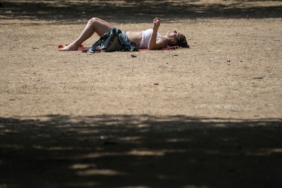 A woman sunbathes in St James&#039;s Park, London, Tuesday July 19, 2022. Britain shattered its record for highest temperature ever registered Tuesday, with a provisional reading of 39.1 degrees Celsi ...