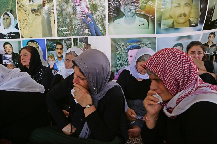 epa07754838 Yazidi ethnic mourner Dyana Faisal 22 years old in (C) cries for her dead family members infront of images of victims, during the fifth anniversary of Yazidi genocide by (IS), in Baadre 25 ...