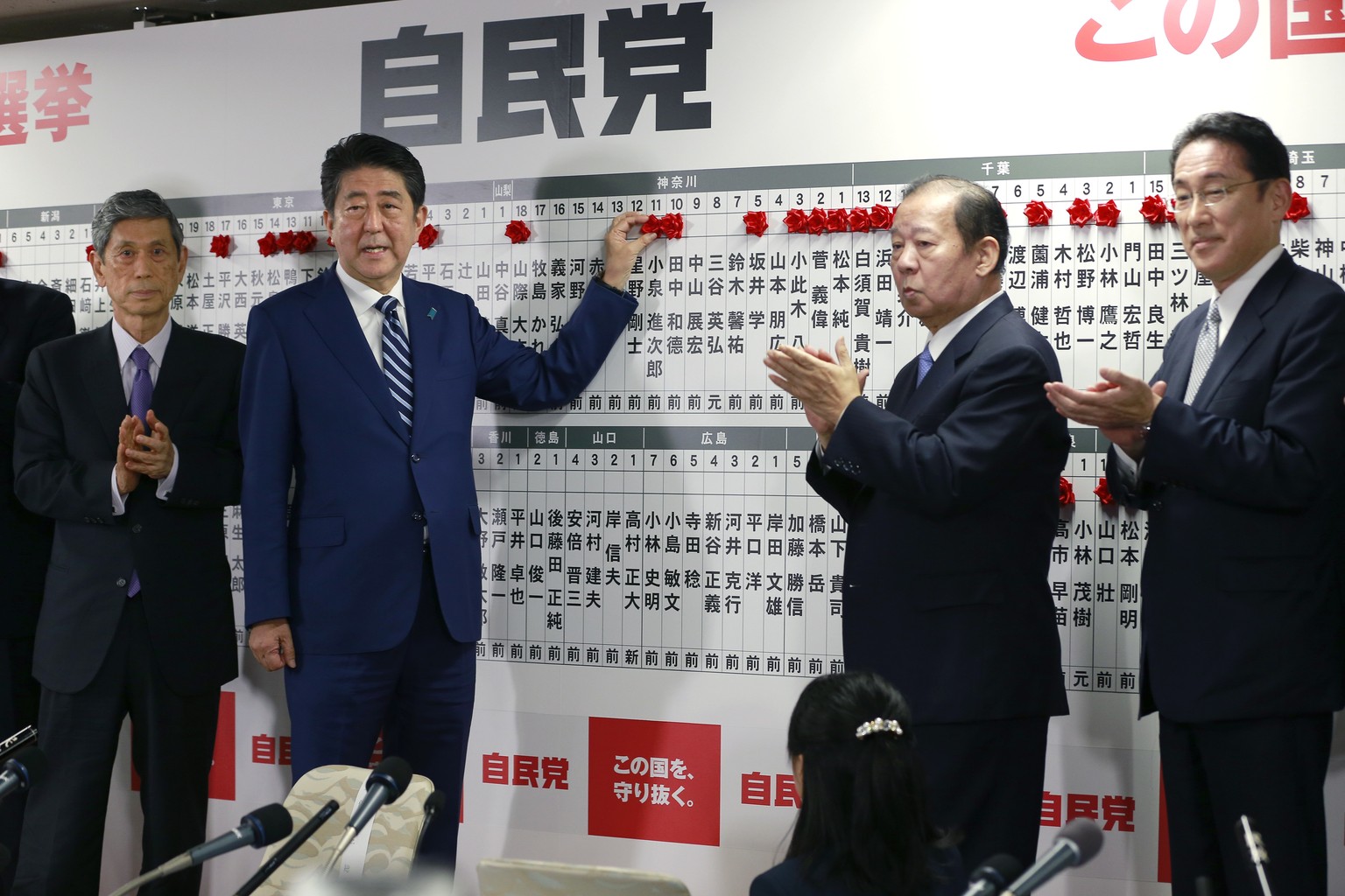 Japanese Prime Minister Shinzo Abe, leader of the Liberal Democratic Party, poses for photos as he marks on the name of one of those elected in the parliamentary lower house election at the party head ...