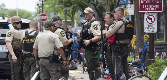 Officers from the Illinois State Police confer near the scene of a shooting involving multiple victims that took place at the Highland Park, Ill., Fourth of July parade Monday, July 4, 2022. (Joe Lewn ...