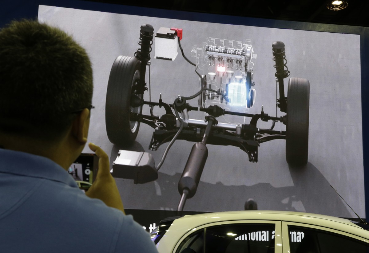 A man looks at a video of the engine of electric and hybrid cars during the first ASEAN electric vehicle and hybrid summit in Manila, Philippines, Thursday, June 29, 2017. The summit aims to highlight ...