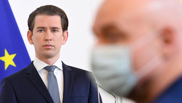 epa08345498 A journalist wearing a face mask is seen next to Austrian Chancellor Sebastian Kurz during a press conference at the Austrian Chancellery in Vienna, Austria, 06 April 2020. Kurz announces ...