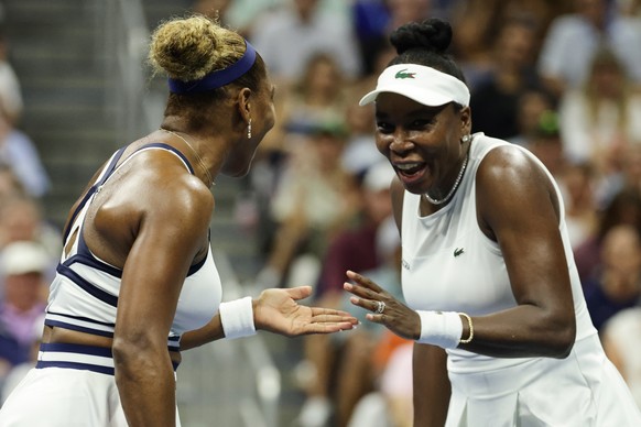 Venus Williams, right, and Serena Williams, of the United States, slap hands during the third set as they play against Hao-Ching Chan, of Taiwan, and Maya Joint, of Australia, during a women's do ...