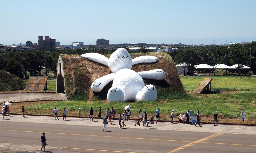 epa04386102 Taiwanese flock to see the 25-meter White Rabbit created by Dutch artist Florentijn Hofman leaning against an old aircraft hangar in Taoyuan County, northern Taiwan, 05 September 2014. Hof ...