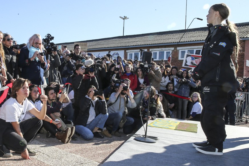 epa08041618 The 16-years old Swedish activist Greta Thunberg (R)delivers a speech upon arrival at Santo Amaro Dock, in Lisbon, Portugal, 03 December 2019. Thunberg crossed the Atlantic on the catamara ...