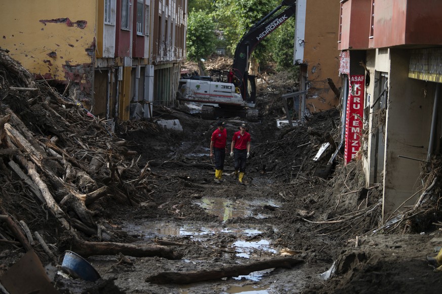 Rescue workers walk in a street in Bozkurt town of Kastamonu province, Turkey, Sunday, Aug. 15, 2021, after flooding. Turkey sent ships to help evacuate people and vehicles from a northern town on the ...