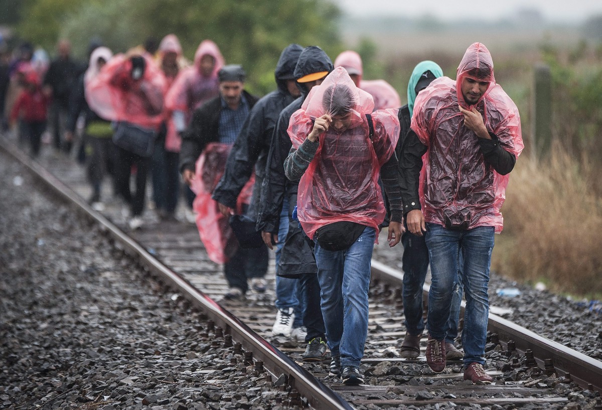 epaselect epa04924313 Migrants walk along the railway crossing in the vicinity of Roszke, at the Hungaro-Serbian border, Hungary, 10 September 2015. More than 200,000 asylum-seekers have arrived in Gr ...
