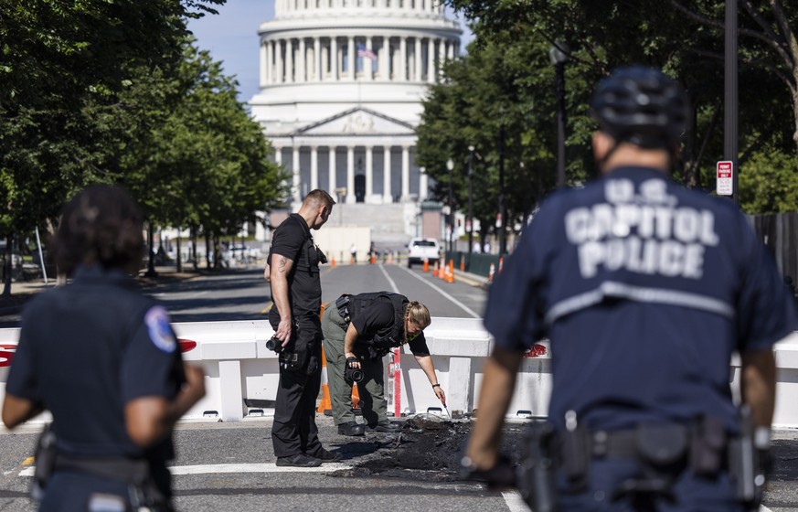 epa10120604 US Capitol police inspect where a burning car crashed into a US Capitol barricade in Washington, DC, USA, 14 August 2022. The driver of the vehicle reportedly fired a weapon at Capitol pol ...