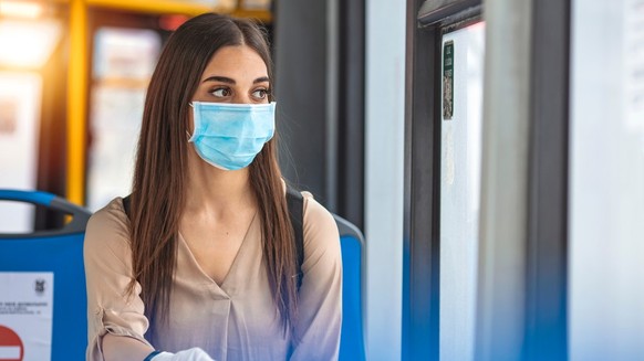 Eine Frau mit Maske und Handschuhen im Bus.
