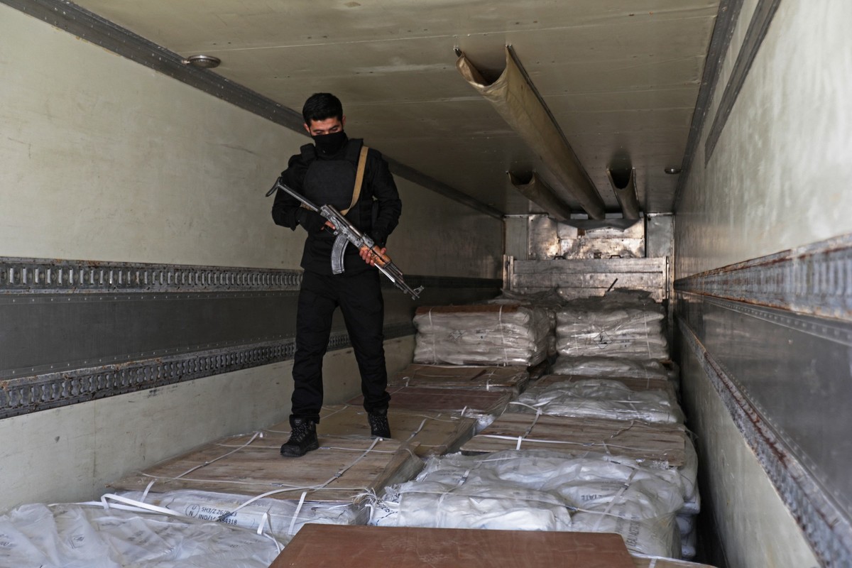 Un membre des forces de sécurité des nouvelles autorités syriennes monte la garde sur des boîtes de pilules de Captagon trouvées dans un complexe des forces du président déchu Bachar al-Assad à Damas  ...