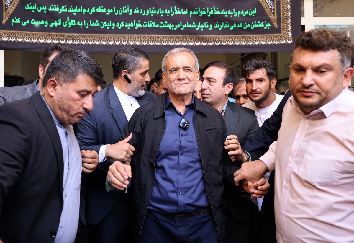 epa11461407 (FILE) - Iranian reformist presidential candidate Masoud Pezeshkian (C) is escorted after casting his vote at a polling station during the presidential election in Ghaleh Hasan Khan, Iran, ...
