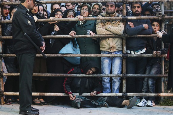 Eine Menschenmenge wartet auf die Hinrichtung. Am Boden die Mutter des Täters.